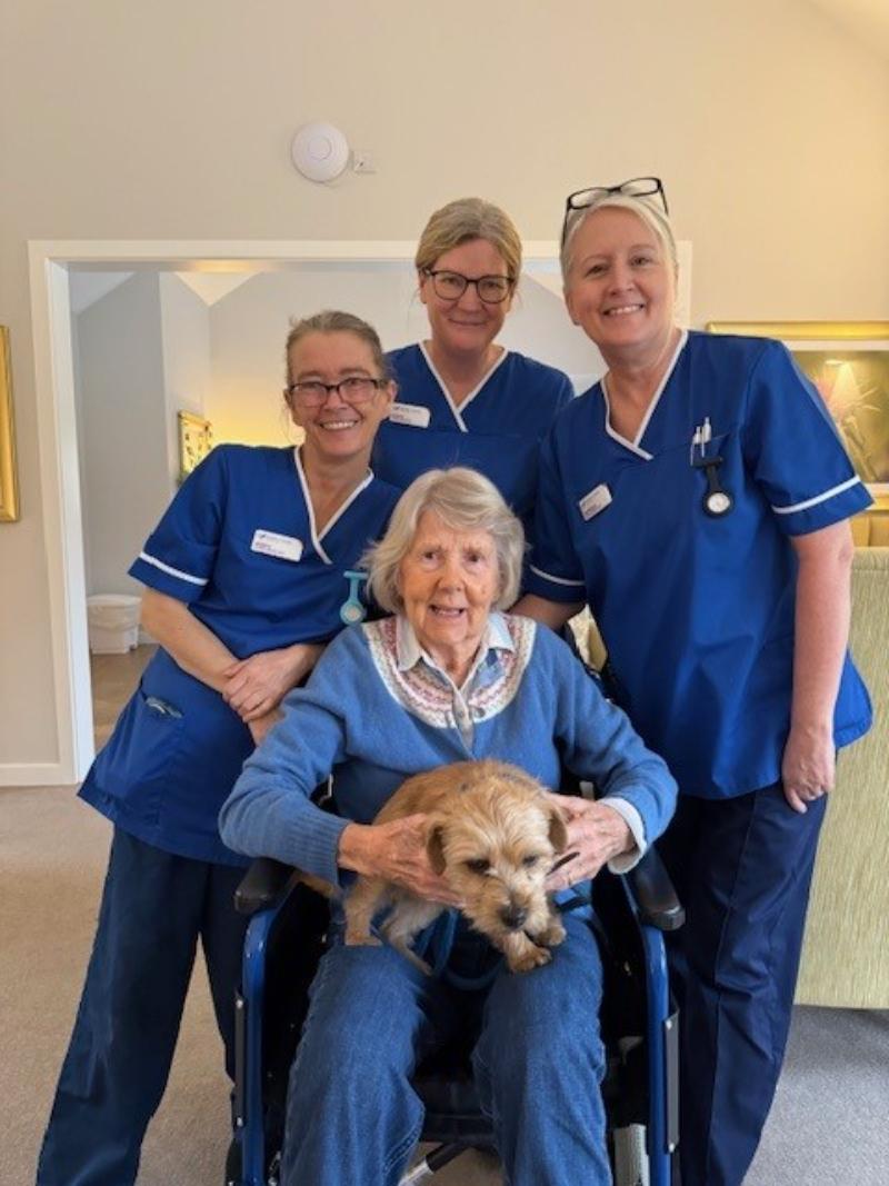 Care home staff with resident in wheelchair and therapy dog