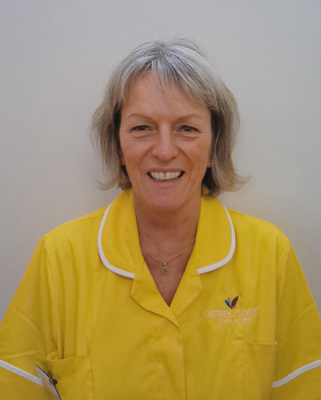woman smiling in yellow care home uniform