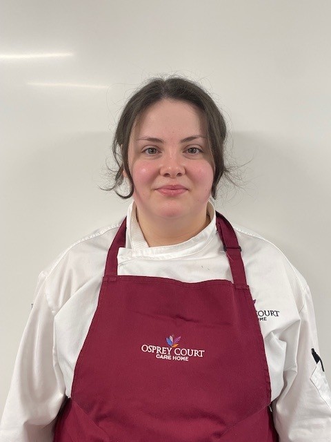 lady wearing red apron smiling at camera