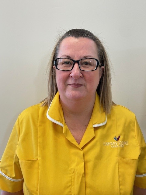 lady with glasses in yellow top looking at camera for staff photo