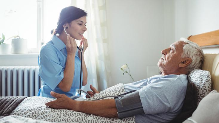 a nurse with an older man who is sat in his bed
