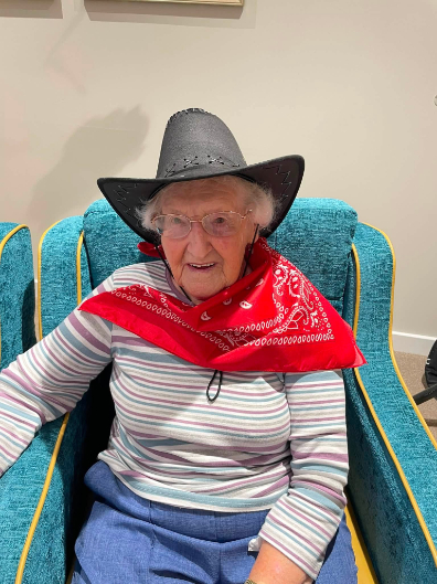 resident sitting on a blue chair smiling and enjoying west hoedown event